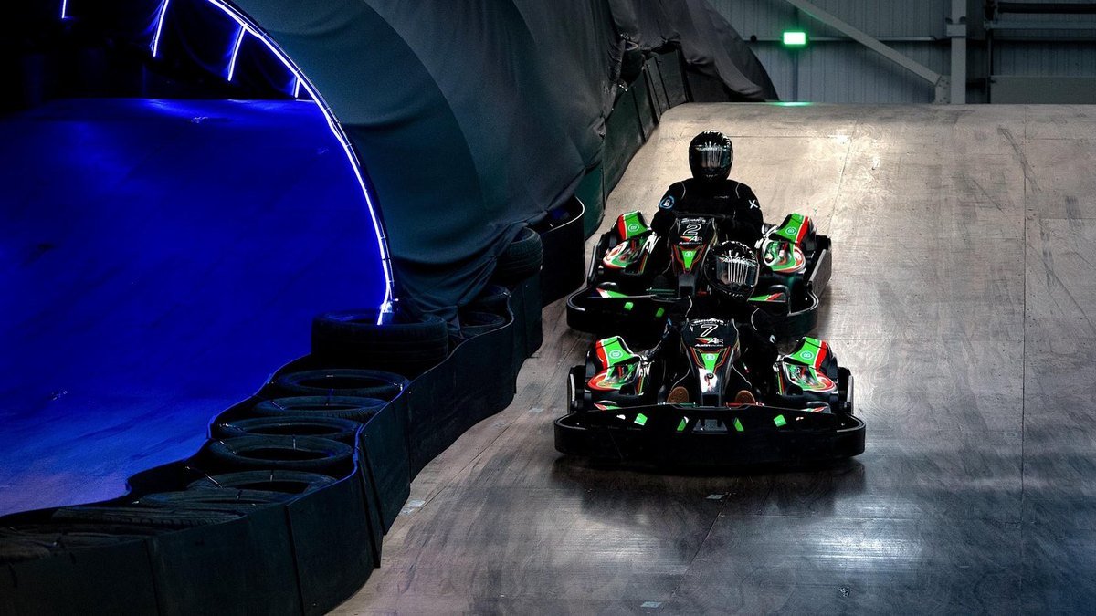 Karts on the inclined section beside the blue-lit tunnel at AR Kartz