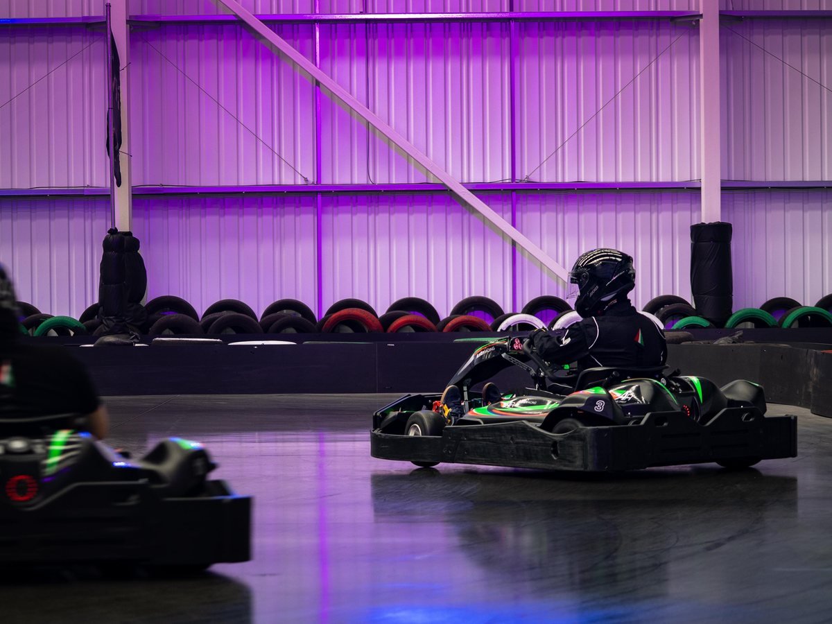 A kart at speed against the purple-lit wall and tyre barriers at AR Kartz