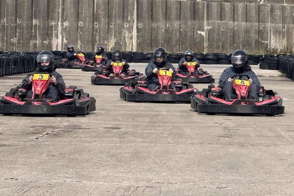 A full grid of red and black karts lined up on the outdoor circuit at Formula Kart Blackpool, tyre barriers along the concrete wall behind