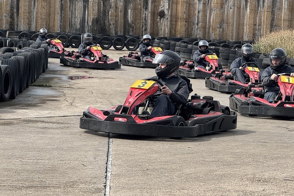 Karts racing through a corner at Formula Kart Blackpool, with the field strung out behind along the tyre wall