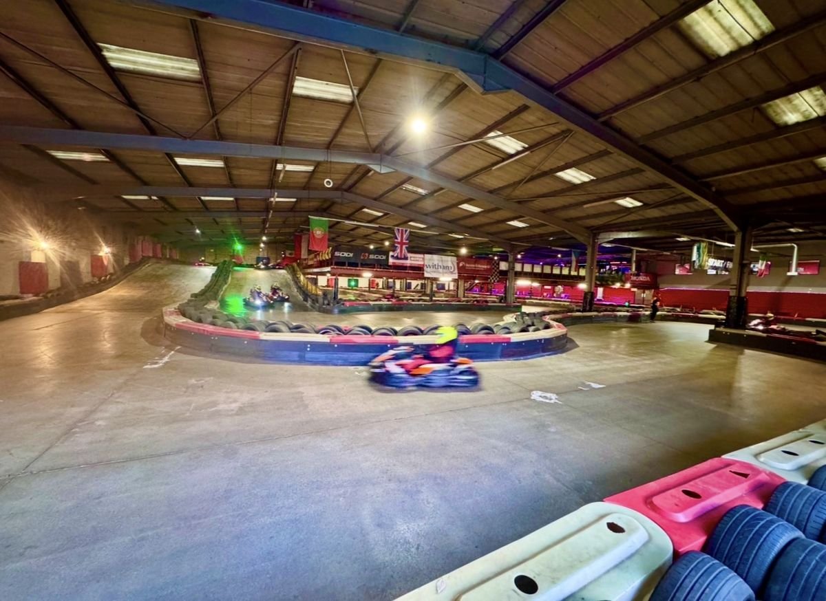 Wide view across the indoor circuit at Gridline Racing in Lincoln, with a kart mid-corner