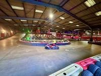 Wide view across the indoor circuit at Gridline Racing in Lincoln, with a kart mid-corner