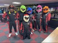 A group in race suits and novelty helmets at Gridline Racing