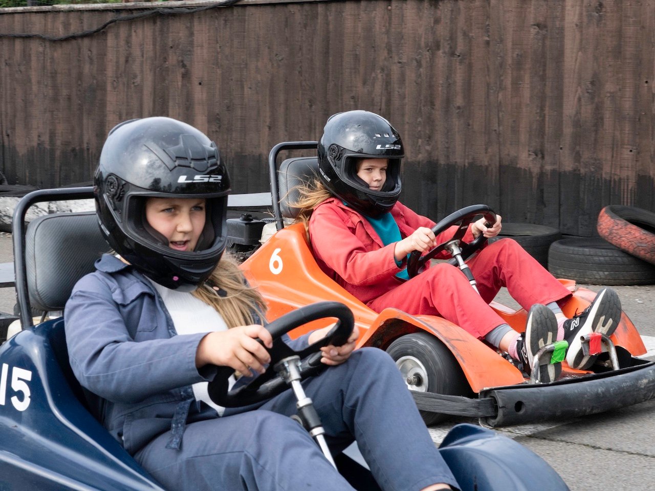 Two junior drivers in helmets and overalls at the wheel of karts at Heatherton World of Activities