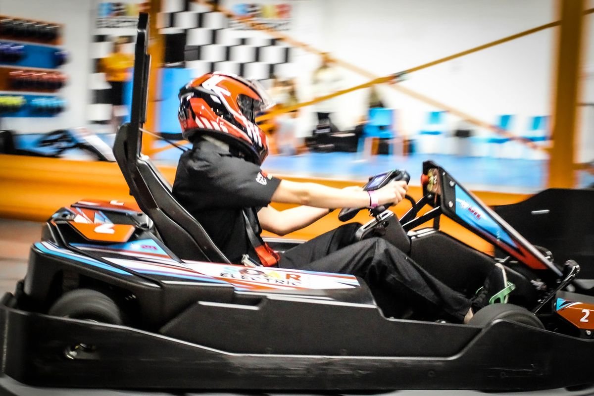 Driver at speed in a SOAR electric kart, shot side-on from track level