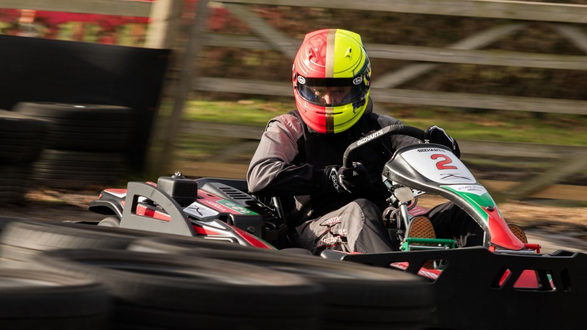 A driver in a red and yellow helmet racing kart number 2 at South Coast Karting